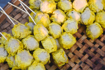several pieces of food arranged on green trays.The dumplings are neatly arranged in rows on the trays, which are placed on a wire rack.