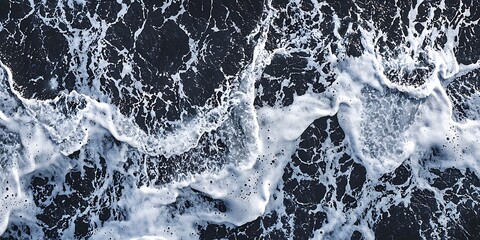 Obraz premium Aerial view of ocean waves, showcasing white foam crashing over deep blue water, creating a dynamic and textured seascape.