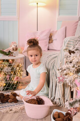The photo shows a girl with a beautiful hairstyle in a light dress, next to a decorated Christmas tree, lights and a Christmas atmosphere.