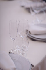 Table setting with white plates, glasses and napkins on beige table. Empty plates and glasses. ready to party
