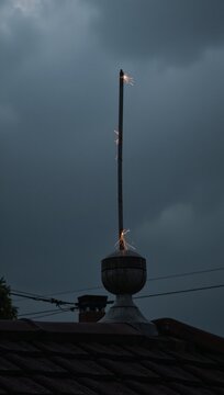 Storm-wracked rooftop with lightning rod offering protection and safety amidst swirling energy of wet weather