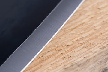 Close up of knife blade on wooden cutting board with copy space.