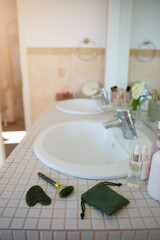 A bathroom counter with skincare bottles, serums, and beauty tools near a sink, highlighting a clean, organized space for a beauty routine. Perfect for lifestyle and beauty ads.