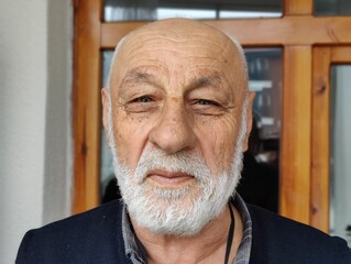 Portrait of an elderly man with a thoughtful gaze, symbolizing wisdom, resilience, and a life full of experiences etched in each line on his face, capturing the dignity and strength of age.