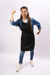 Young woman wearing apron and celebrating success. Full length portrait of a chef standing with raised hands on a white background, vertical