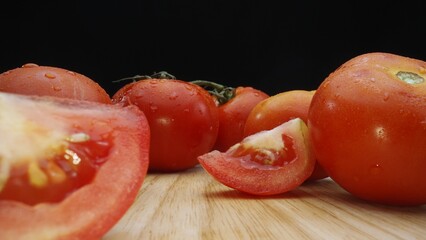 Macrography, slices of tomato rest elegantly on a rustic cutting board against a dramatic black background. Each close-up shot captures the juicy texture and rich colors of the tomatoes. Comestible.