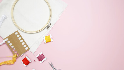 Beige cotton cloth in embroidery hoop with fabric, colorful threads, scissors and needls. Embroidery set fot stitching © matucha12