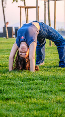 A slightly overweight teenage girl doing gymnastics in a grassy park on a summer day