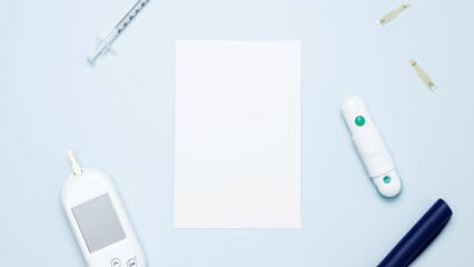 Diabetes concept with glucometer, syringe pen with insulin, blood test strips. Concept of worldwide diabetes awareness. Mock up white paper