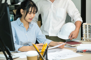 Obraz premium Engineers looking and discussing over blueprints on desk.