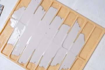 Pouring gypsum into a mold for making decorative bricks.