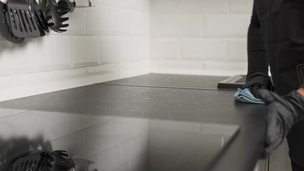 Close-up cleaner wipes a kitchen counter, maintaining hygiene. General cleaning