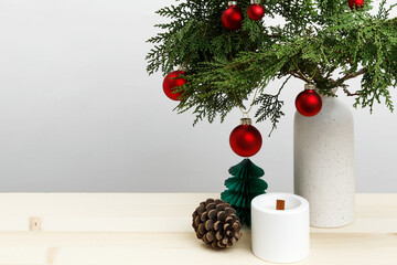 Vase with thuja branches, Christmas ornaments, pinecone, and candle for festive decor