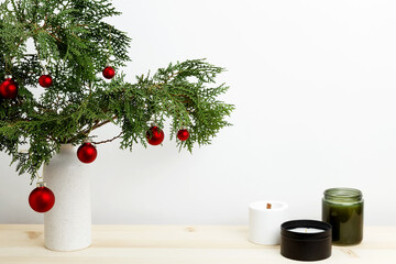 Vase with thuja branches, Christmas ornaments, pinecone, and candle for festive decor