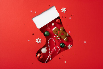 Obraz premium A playful Christmas sock cutout filled with festive items like ornaments, a gingerbread man, and candy canes showcasing holiday spirit and creativity