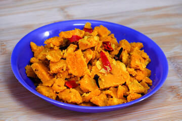 The side view of Gujarati Kathiyawadi Spicy Dhokali Pieces Sabji emphasizes the blue dish's special qualities