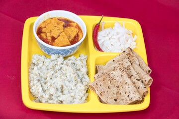 Right Side view of Gujarati Kathiyawadi Spicy Dhokali Sabji with khichdi, on yellow dish prominently, set against a black background
