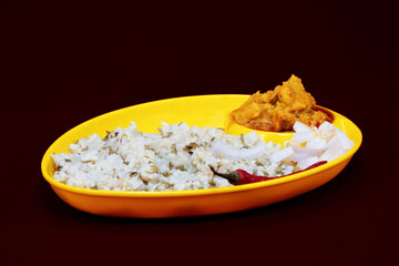 Right Side view of Gujarati Kathiyawadi Spicy Dhokali Sabji with khichdi, on yellow dish prominently, set against a black background