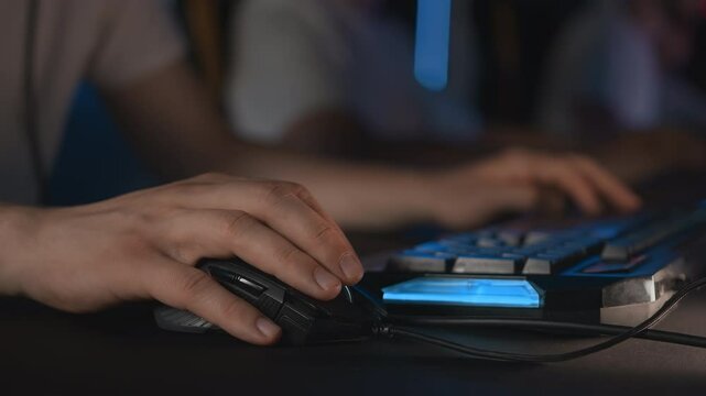 Gamers play video game on PC at computer club, professional cyber sport tournament, gaming mouse RGB lighting keyboard on mat close up. E-sport championship. Multiplayer first-person shooter strategy
