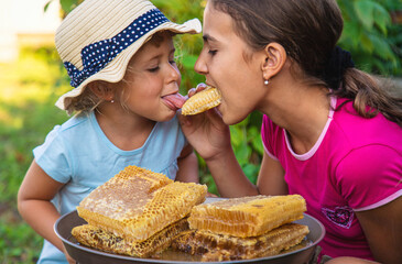 A child eats honey from a comb. Selective focus.