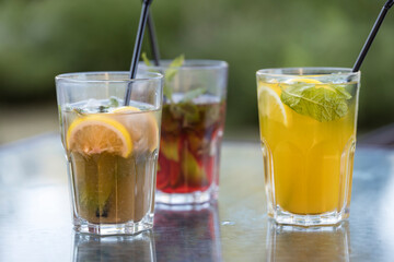 Three glasses of different colored drinks sit on a table