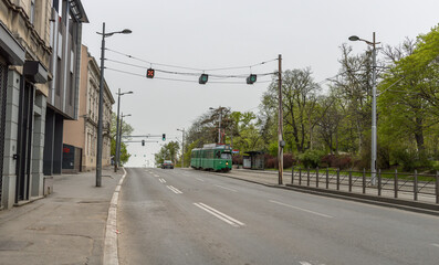Green trolley is traveling down a street in a city