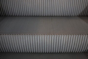 Close-up escalators in neutral tones, highlighting symmetrical design and textured steps. Modern urban transportation infrastructure detail, material background