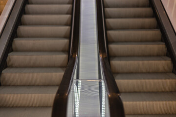Close-up view of parallel escalators in neutral tones, highlighting symmetrical design and textured steps. Modern urban transportation infrastructure detail