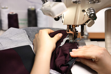 Young woman with sewing machine working in professional workshop, closeup