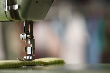 Vintage sewing machine with thread and fabric on blurred background, macro view. Space for text