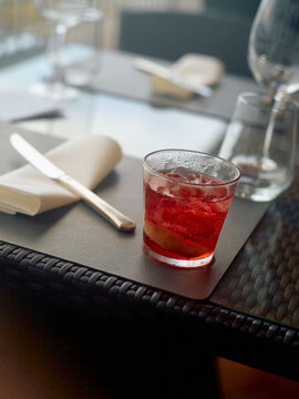 A refreshing cocktail on a textured table at an upscale restaurant with elegant cutlery and glassware in soft focus background, Naples, Italy