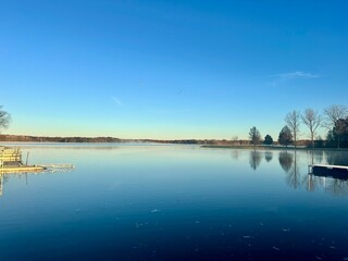 Blue reflective glass lake during the dawn with yellow and autumn trees.
