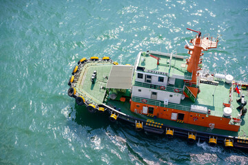 Aerial view of an orange and green tugboat on crystal blue waters, Singapore
