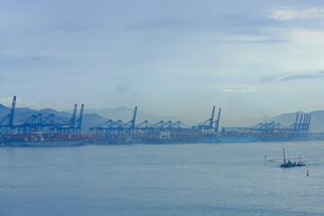 Misty view of a harbor with cranes and a small boat on tranquil waters at dawn, Busan, Korea