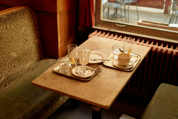 A cozy retro vintage coffee table setup with finished drinks and open books in an intimate cafe setting.