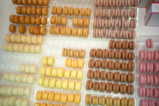 Assorted macarons arranged in neat rows within transparent boxes in a shopping window display