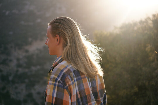 a young man with long blond hair glowing in the sun. Healthy long hair for a man