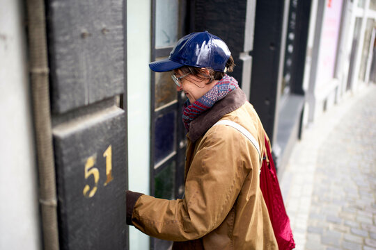 Young woman with a blue shiny hat entering a building with the number 51