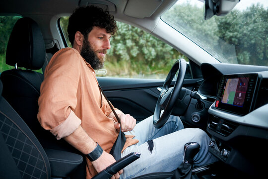 Man with curly hair focused on driving a car with a modern interior and touchscreen display.
