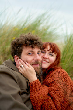 A smiling couple embraces warmly amidst tall grass with affection and contentment evident on their faces, Belgium