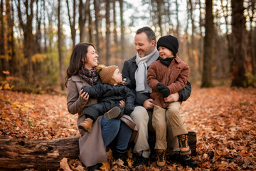 Joyful family and childs having fun, laugh and enjoy nature outdoors at autumn park.