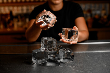Close-up of the hands of a female bartender, demonstrating an ice cube in both hands