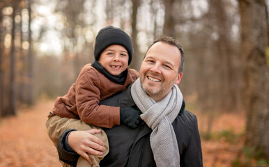 Joyful dad and his child boy. daddy and child have fun, laugh and enjoy nature outdoors at autumn park.