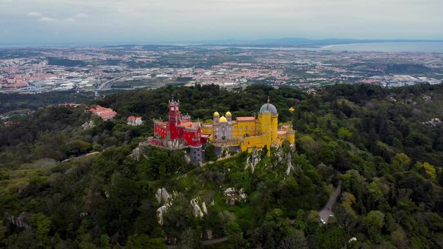 Famous National Palace of Pena situated in Sintra, Portugal. City of Sintra and Lisbon in background. Famous travel destination. The palace is a UNESCO World Heritage Site. Drone going backword. 