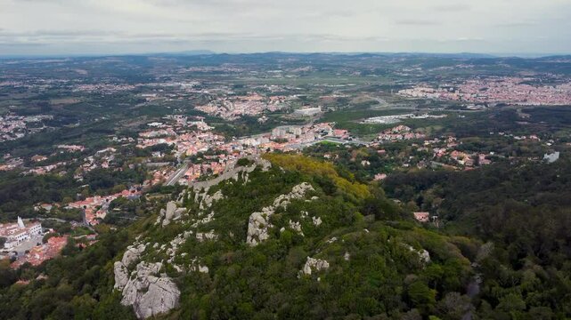 Aerial drone view of The Moorish Castle, Sintra, Portugal. Hilltop medieval castle built by the Moors in the 8th and 9th centuries. In background is Sintra city. Travel destination. Drone forward.