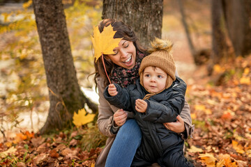 Joyful mother and his little baby. mother and child have fun, laugh and enjoy nature outdoors at autumn park.