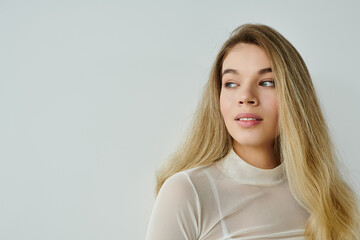 A young woman with long hair exudes calmness and beauty in a minimalist space.