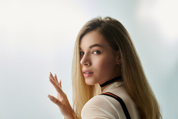 A young woman gazes back with a soft smile, illuminated by gentle light in an artistic setting.