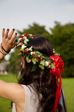Ragazza con corona d&rsquo;alloro decorata con fiori rossi e bianchi e un fiocco rosso