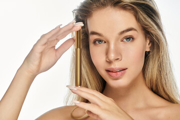 Fototapeta premium A smiling young woman showcases her skincare routine with a golden serum.